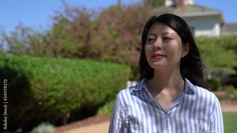 quick movement confident asian woman happy relaxing walking in the garden in front her house on sunny day. young elegant office lady enjoy beautiful green nature in summer going to work smiling. quick movement confident asian woman happy relaxing walking in the garden in front her house on sunny day. young elegant office lady enjoy beautiful green nature in summer going to work smiling.