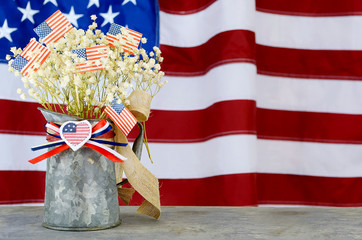 A bouquet of babies breath and US flags in a tin pitcher in front of a larger flag in the background. Good for any US holiday.