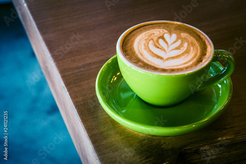 cappucino in a green cup and saucer with foram art in the shape of a leaf photo