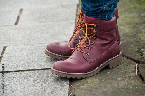 closeup of feet of woman with red winter boots on cobblestone in the street