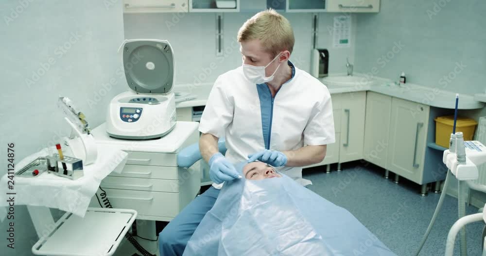 Vampire facelift procedure in a modern clinic doctor starting the procedure for a man who is laying down on the chair , doctor taking the micro-needing and it s ready to start face procedure. Vampire facelift procedure in a modern clinic doctor starting the procedure for a man who is laying down on the chair , doctor taking the micro-needing and it s ready to start face procedure.
