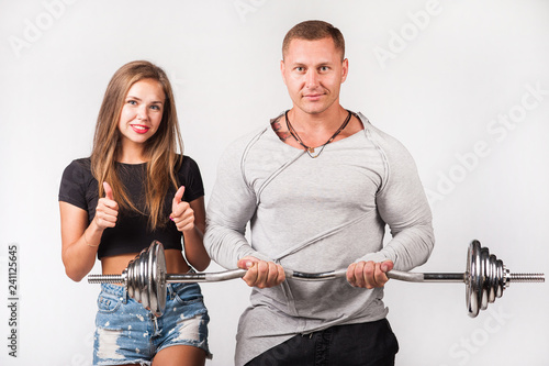 Athlete man holds the barbell in the hands of the girl holds his thumbs up