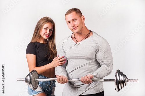 Male athlete holds barbell in hands girl touches his biceps