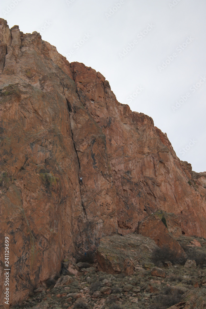 man climbing red rock mountain