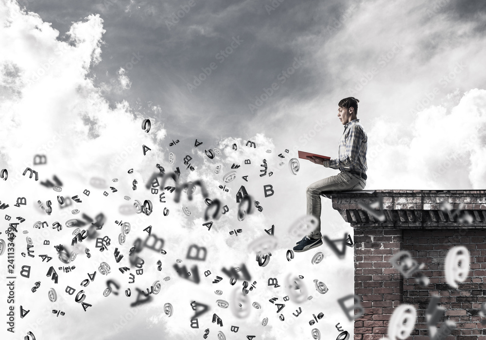 Man on roof edge reading book and symbols flying around Man on roof edge reading book and symbols flying around