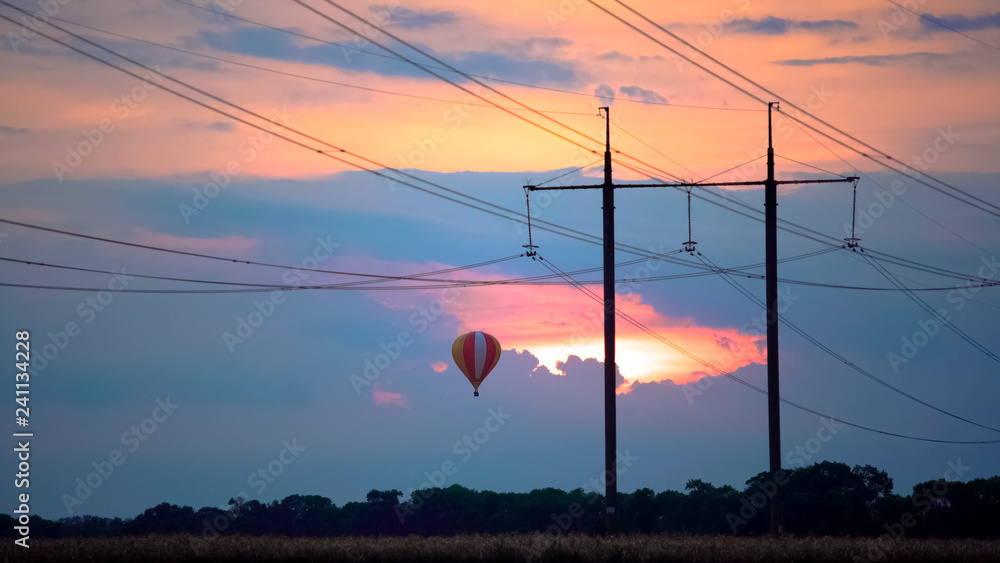 Fantastic view of beautiful hot air balloon flying in glowing sunset sky, beauty
