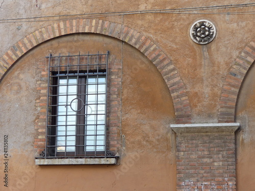 Finestra di un palazzo medievale con sbarre di ferro incorniciata da un arco a Roma in Italia.