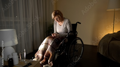 Upset lady in wheelchair thinking about children, abandoned patient nursing home