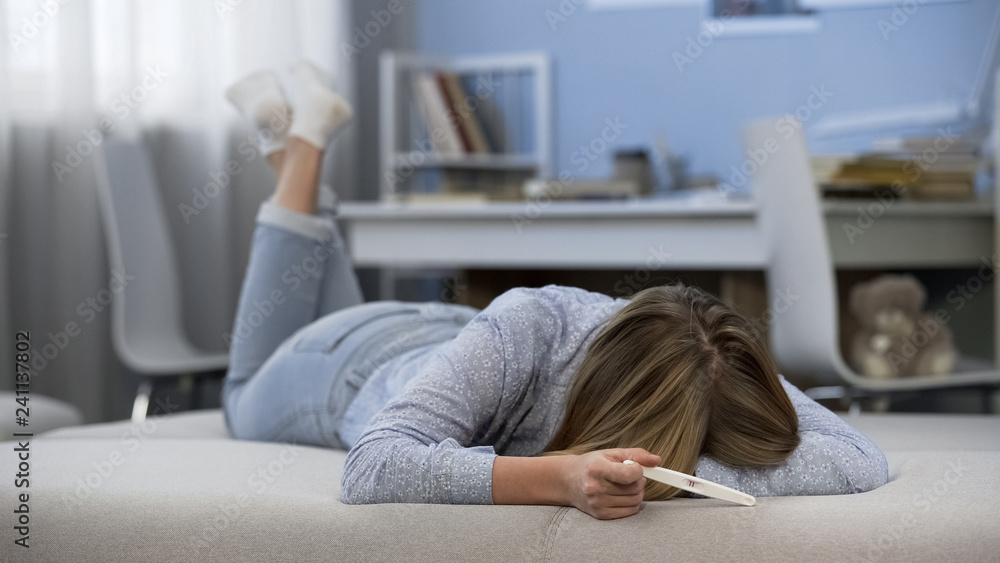 Teen girl crying because of early pregnancy, feeling desperate, unwanted baby Teen girl crying because of early pregnancy, feeling desperate, unwanted baby