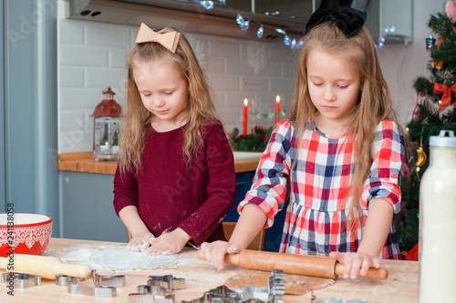 Adorable happy little girls baking Christmas gingerbread cookies in Xmas eve