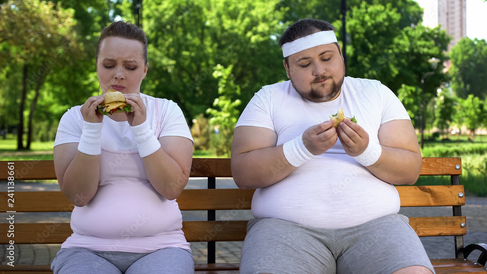 Fat couple eating burgers, feeling guilty for stopping diet, fast food