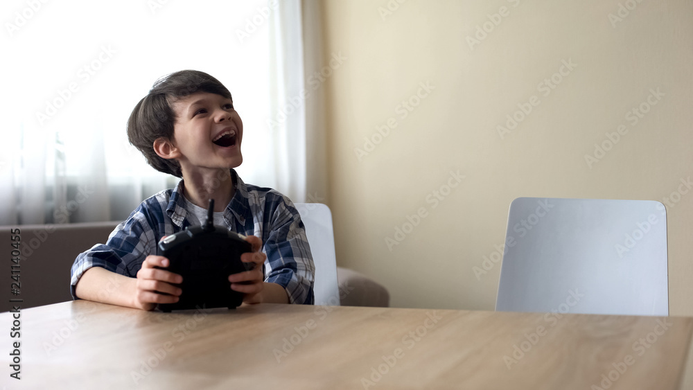 Cheerful boy operating drone with remote control, rejoicing cool b-day gift Cheerful boy operating drone with remote control, rejoicing cool b-day gift