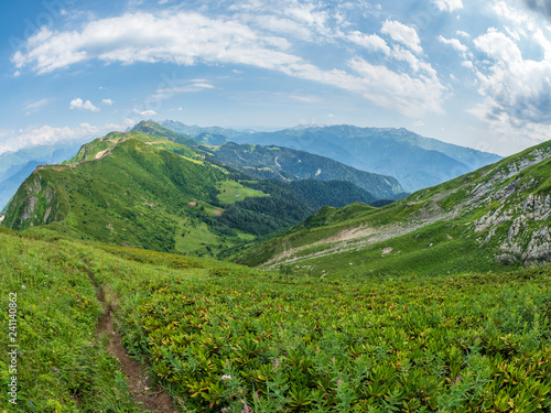 View over the Green Valley, surrounded by high mountains on a clear summer day. Krasnaya Polyana, Sochi, Caucasus, Russia. © Dmitrii Potashkin