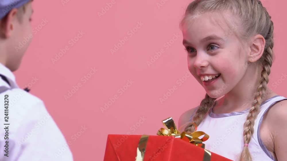 Boy presenting gift to his surprised girlfriend, romantic date on Valentines day Boy presenting gift to his surprised girlfriend, romantic date on Valentines day