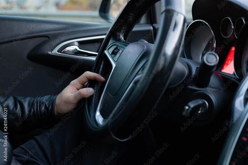 Male driver holding steering wheel while driving
