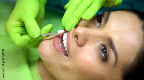 Stomatologist comparing color of natural tooth with sealant filling, closeup