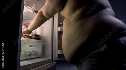 Fat belly man taking sandwich from kitchen fridge, diet failure, junk food