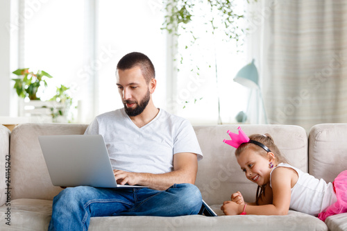Father with daughter spending time at home, man using laptop and girl digital tablet