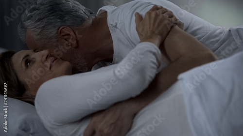 Aged male kissing woman neck  couple hugging and caressing in bed  attraction