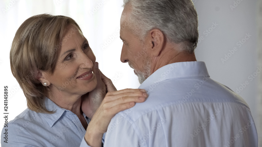 Elderly lady with perfect skin looking husband, husband stroking her happy face Elderly lady with perfect skin looking husband, husband stroking her happy face