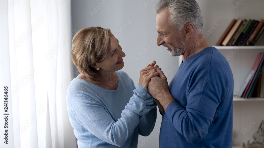 Fototapeta premium Happy aging couple looking at each other and smiling, trustful relationship