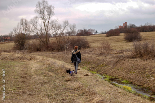 Girl with little dog walk near the river through park in winter without snow © Milan
