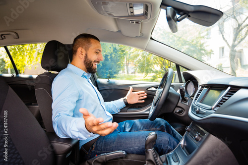 Side view of happy and surprised young businessman driving driverless car