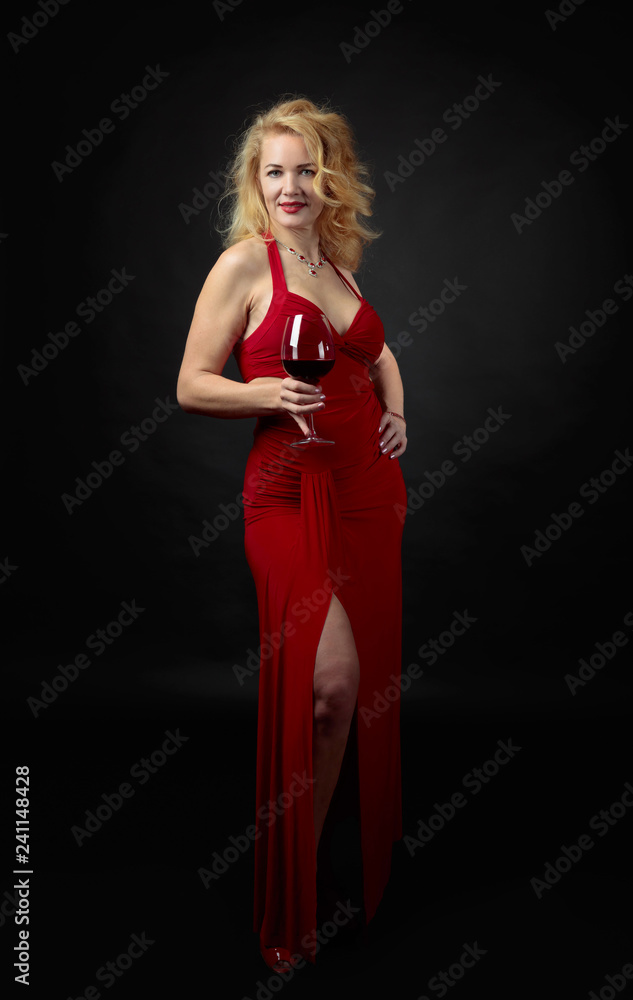 Attractive middle age woman in red evening dress with glass of red wine. Attractive middle age woman in red evening dress with glass of red wine.