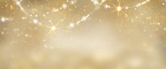 Christmas golden glowing background. Holiday abstract glitter defocused backdrop with blinking tars and garlands. Blurred gold bokeh