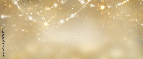 Christmas golden glowing background. Holiday abstract glitter defocused backdrop with blinking tars and garlands. Blurred gold bokeh photo