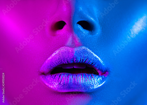 Beautiful sexy girl, trendy glowing makeup, metallic silver lips. High fashion model woman in colorful bright neon lights posing in studio. 