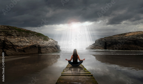 Fotografi Woman in yoga pose in front of the sea
