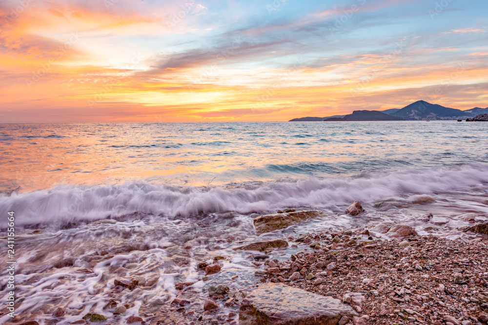 Obraz premium Vibrant sunset at the beach - in Sveti Stefan