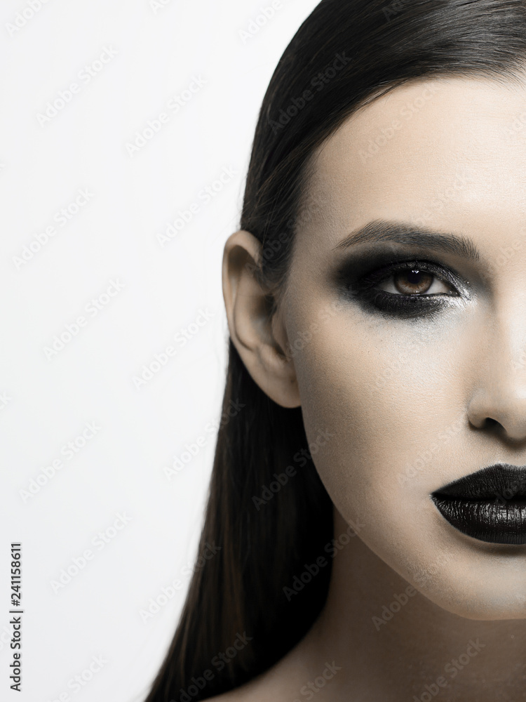 Naklejka premium Black and white photograph of the terrible beauty of the model, like from a horror movie. Party party, Halloween, creative make-up, smoky eyes and full lips