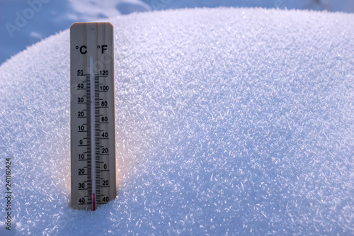 Wooden thermometer on white snow background