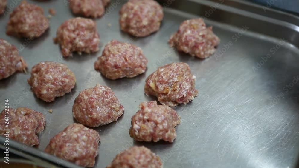Cook cooks meatballs. Raw minced meat spread on a baking sheet in the form of balls. Cook cooks meatballs. Raw minced meat spread on a baking sheet in the form of balls.