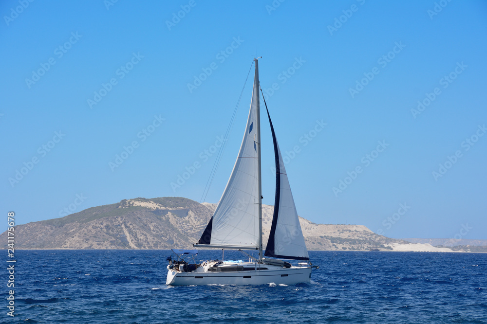 the yacht with a sail at the sea near the island