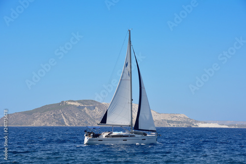 the yacht with a sail at the sea near the island
