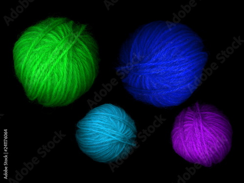 Multi-colored skeins of wool on a black background. Multicolored balls. Colored wool in the balls.