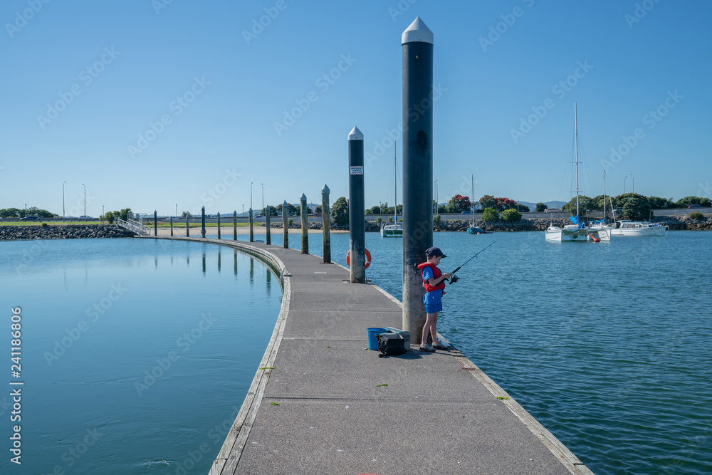 Small boy in red life jacket fishing