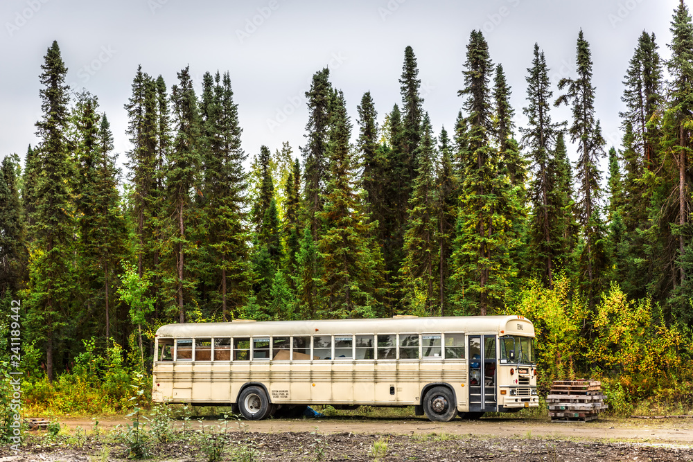 Alaska, USA - Sept 10th 2017 - An abandoned school bus near by a pine tree forest in a cloudy day