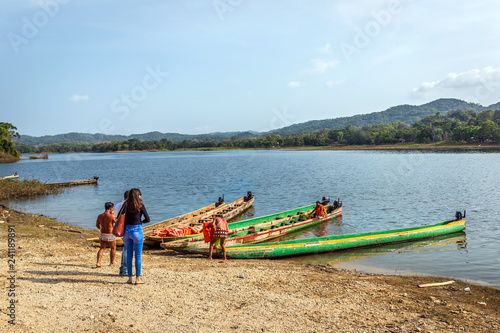 Embera Drua Villiage, Panama - Mar 4th 2018 - Tourists getting on board an indigenous boat in a wide river with a forest in the background in Panama