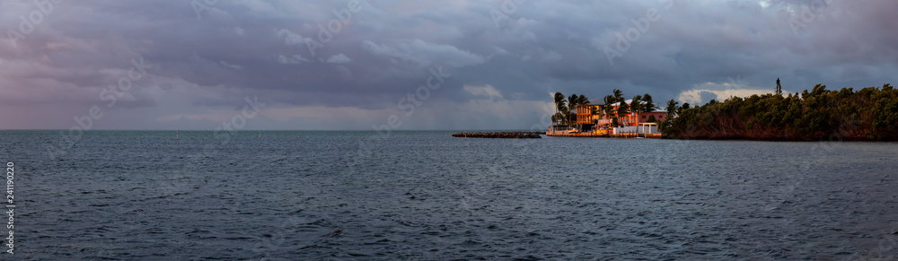 Panoramic view of homes on a tropical Atlantic Ocean Coast during a cloudy sunrise. Taken in Plantation Key, Florida Keys, Florida, United States. Panoramic view of homes on a tropical Atlantic Ocean Coast during a cloudy sunrise. Taken in Plantation Key, Florida Keys, Florida, United States.