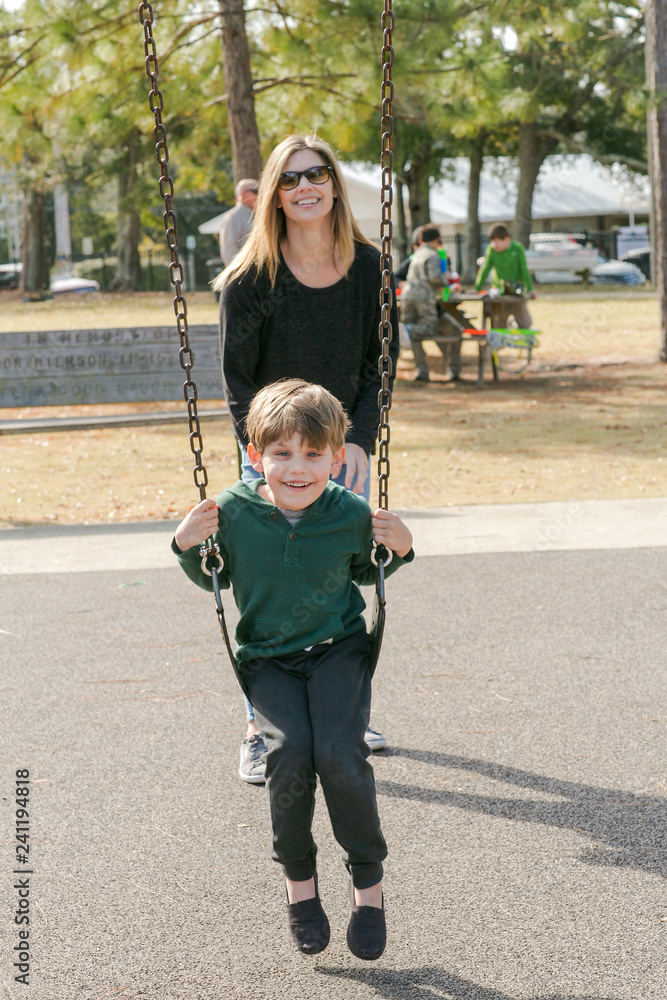 Mom Pushing Son Little Boy on the Swings at the Park Playground Mom Pushing Son Little Boy on the Swings at the Park Playground
