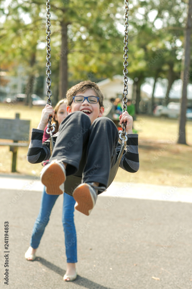 Sister Pushing Son Little Boy on the Swings at the Park Playground Sister Pushing Son Little Boy on the Swings at the Park Playground