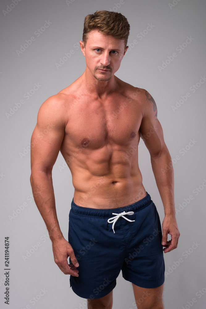 Fototapeta premium Muscular handsome bearded man shirtless against white background