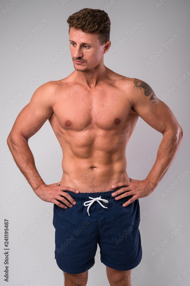 Muscular handsome bearded man shirtless against white background