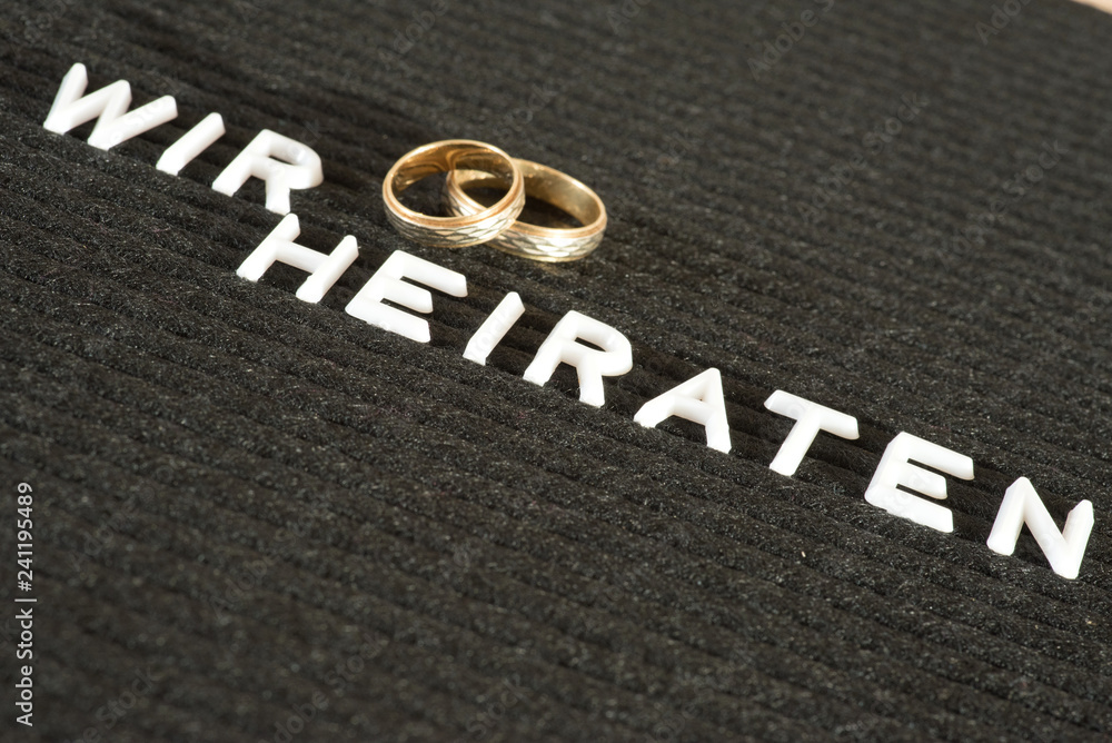 Fototapeta premium Zwei Eheringe und Slogan Wir heiraten