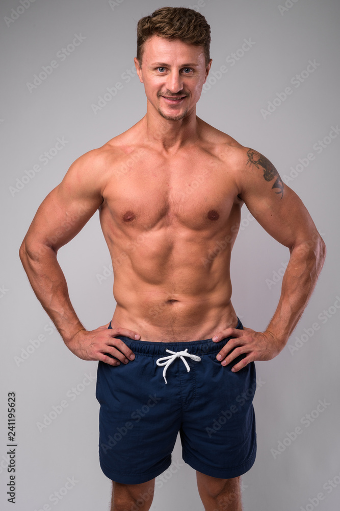 Happy muscular bearded man shirtless smiling against white background