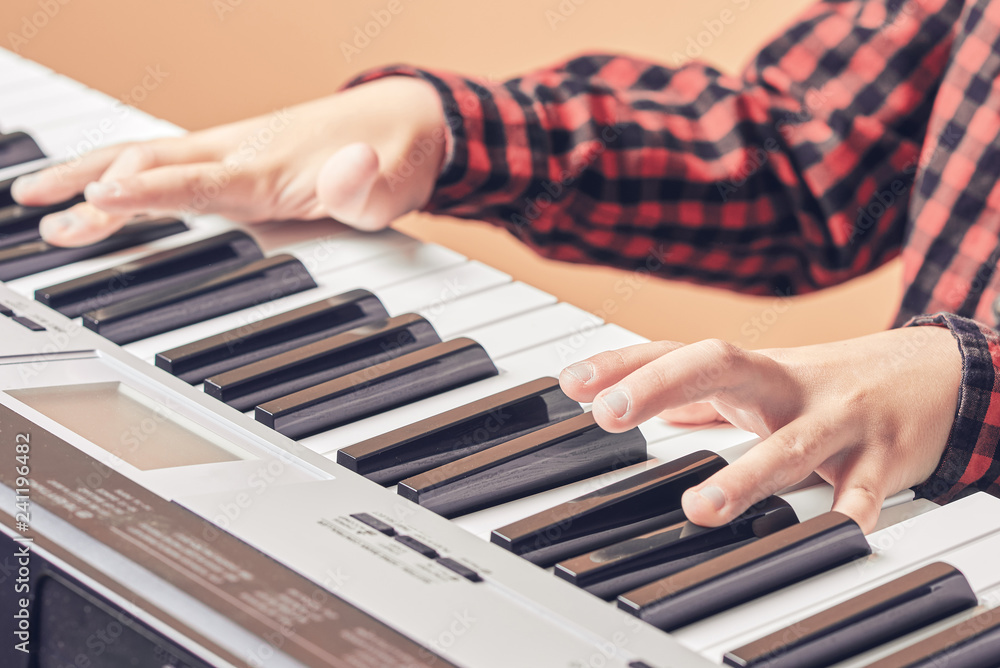 Fototapeta premium European kid is playing electric piano. He has his music lesson. Close view.
